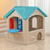 Plastic children’s playhouse with a blue arched door, red window shutters, and a blue roof, designed for indoor or outdoor pretend play (angle view)