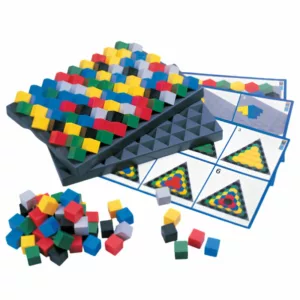 A colorful tabletop puzzle game featuring a black square board filled with small multicolored cubes arranged in geometric patterns. Several challenge cards showing triangular and linear color designs are spread beneath the board, while a pile of loose cubes sits in the foreground.